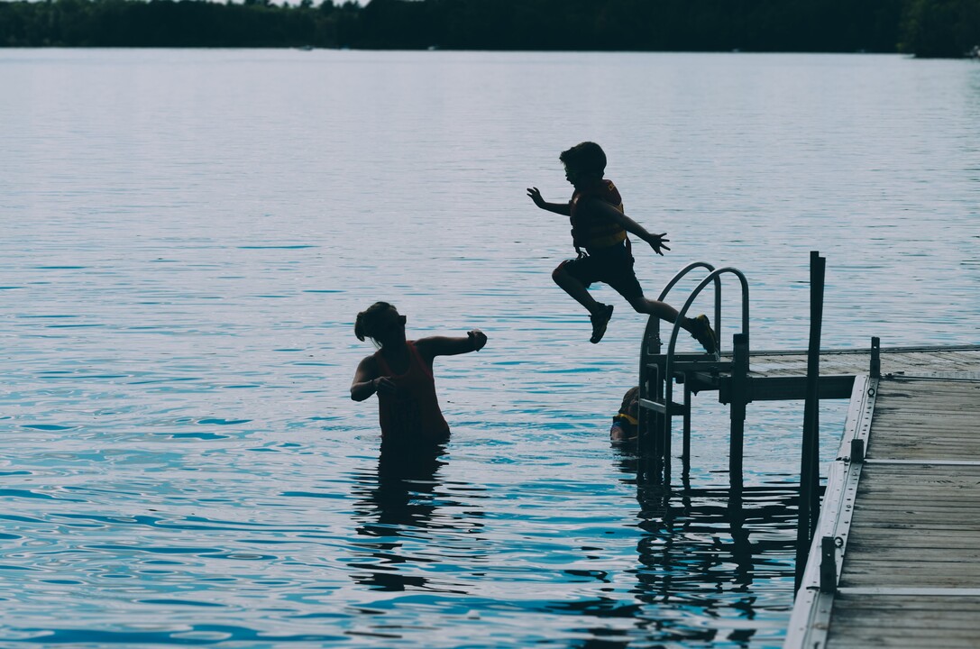 Kid jumping in water, mother ready to help